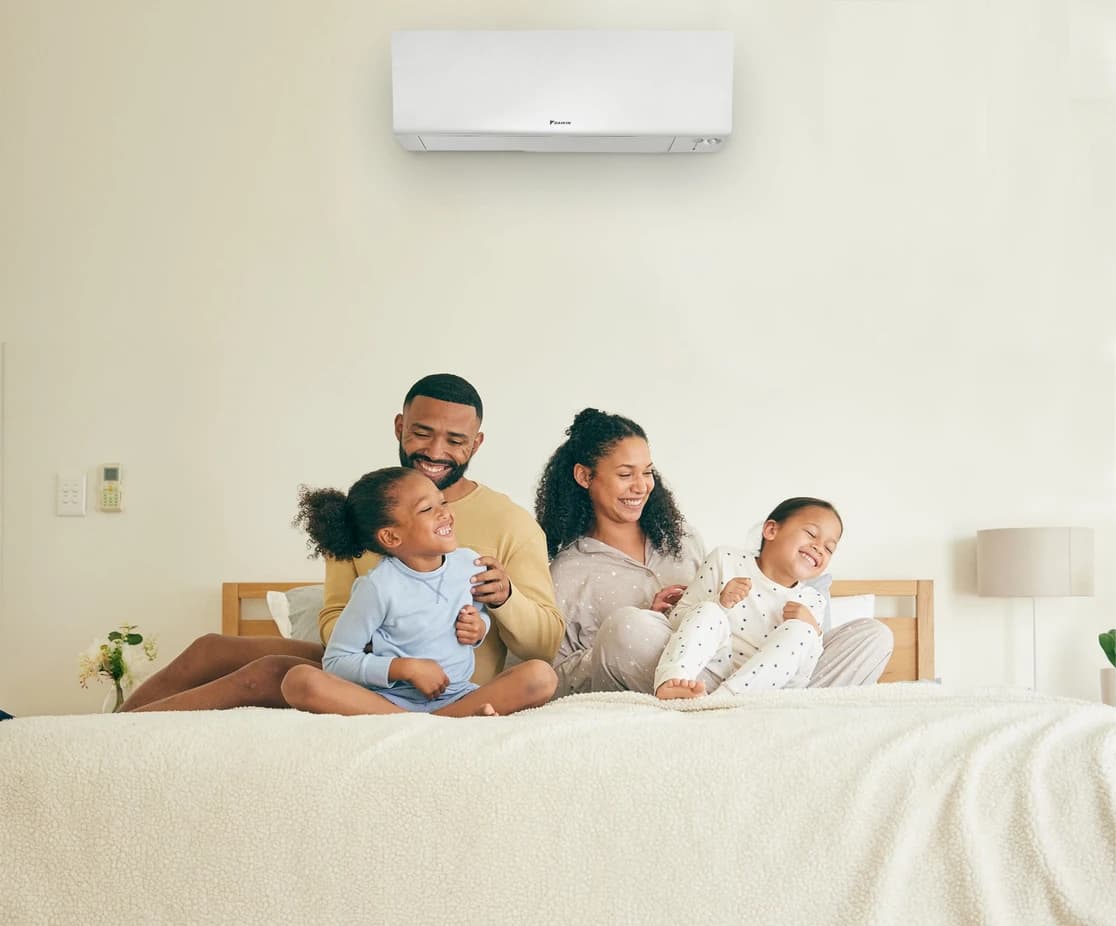 Family relaxing on a bed beneath a wall-mounted Daikin mini-split