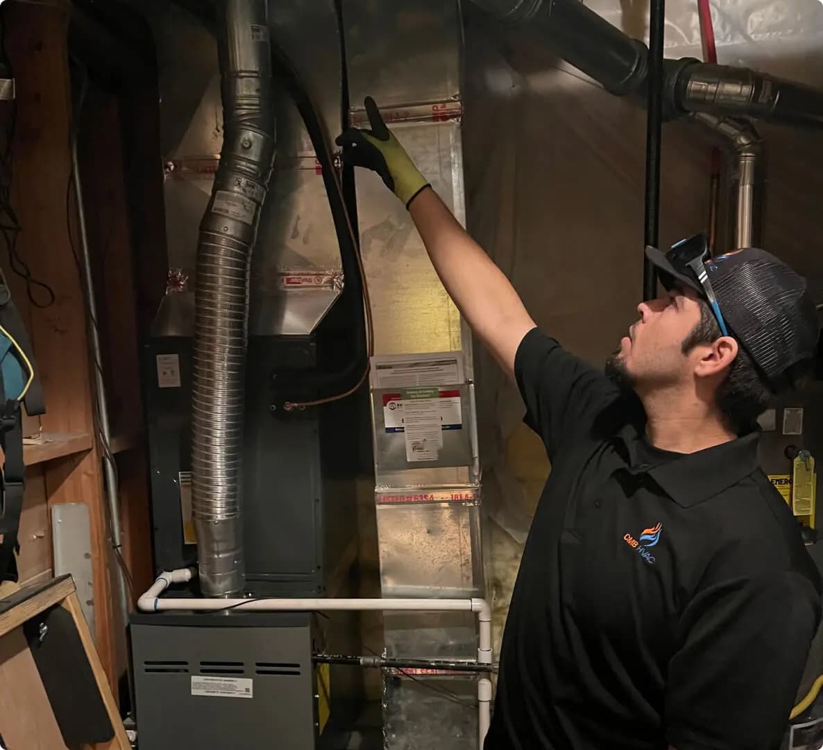 Technician inspecting furnace ductwork in a basement