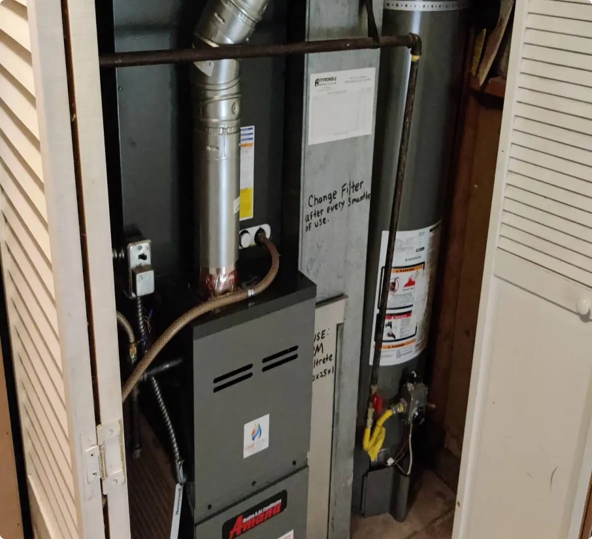 Technician checking a furnace flue pipe in a utility room
